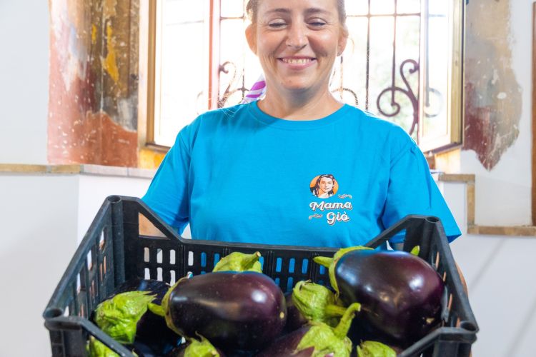 Giovanna mentre mostra una cassetta di melanzane fresche nel negozio MamaGiò di Mosciano Sant'Angelo a Teramo in Abruzzo
